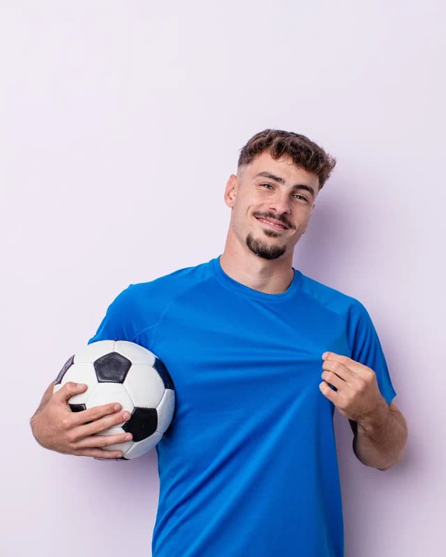 A guy smiling with a soccer ball in his hands